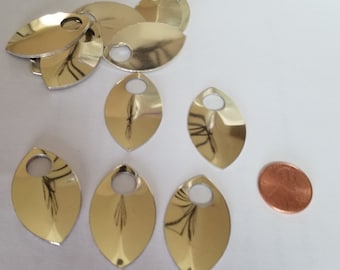 May include: A collection of ten silver-colored metal fish scales with a hole in the center. The scales are arranged in a random pattern on a white surface. A penny is included for scale.