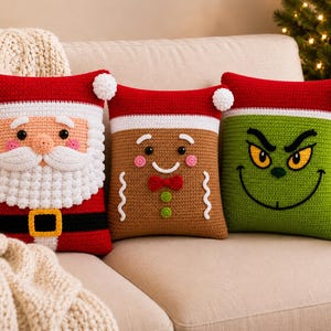 May include: Three square crochet pillows featuring holiday characters. The left pillow is a red Santa with a white beard and black belt. The center pillow is a brown gingerbread person with a red bow tie. The right pillow is a green character.