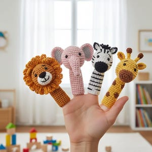 Könnte beinhalten: Gehäkelte Fingerpuppen von Löwe, Elefant, Zebra und Giraffe. Der Löwe ist orange mit braunem Gesicht, der Elefant rosa mit grauen Ohren, das Zebra hat schwarz-weiße Streifen und die Giraffe ist gelb mit braunen Flecken.