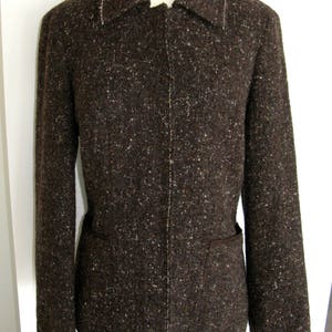 May include: A brown tweed blazer with a zipper closure and a single pocket on each side.