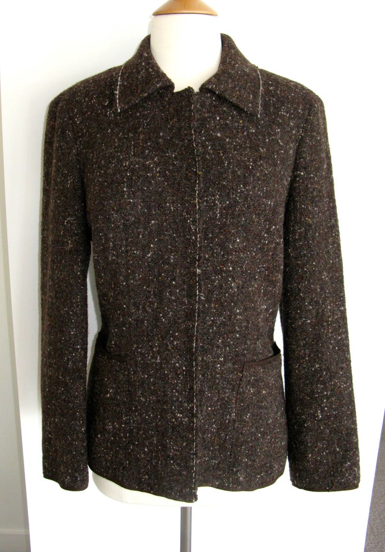 May include: A brown tweed blazer with a zipper closure and a single pocket on each side.