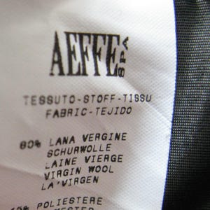 May include: A white fabric label with black text that reads "AEFFE" and "TESSUTO-STOFF-TISSU FABRIC-TEJIDO". The label lists the fabric composition as 80% virgin wool and 15% polyester. The label also includes the number "A05015144".