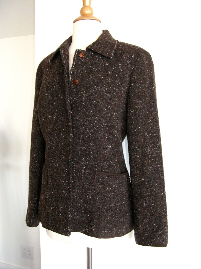 May include: A brown tweed jacket with a button-up front and a patch pocket on the left side.