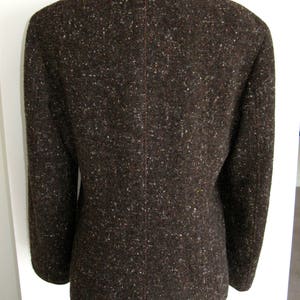 May include: A brown tweed blazer with a white trim around the collar and cuffs.