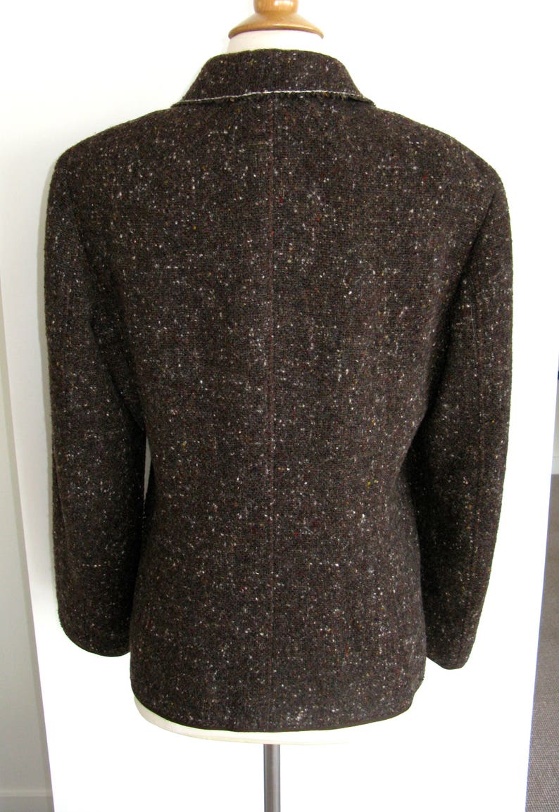 May include: A brown tweed blazer with a white trim around the collar and cuffs.