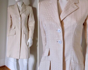 May include: A white long-sleeved jacket with a textured pattern and a single-breasted closure. The jacket has two pockets on the front and a fitted silhouette.