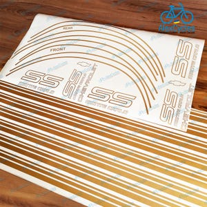 May include: Gold and white decal sheet with the text "SS MONTE CARLO CHEVROLET". The sheet includes curved lines and parallel stripes. The words "REAR" and "FRONT" are also visible.