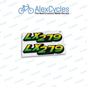 Puede incluir: Dos calcomanías para bicicletas con el texto "LX279" en degradado amarillo y verde con contorno negro. El logotipo de AlexCycles es visible en el fondo.