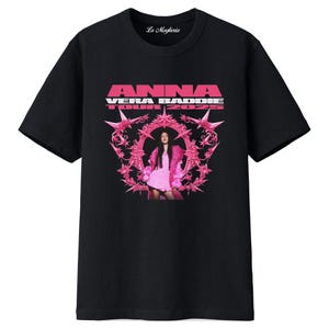 Könnte beinhalten: Schwarzes T-Shirt mit einem rosa Aufdruck mit der Aufschrift "ANNA VERA BADDIE TOUR 2025". Die Grafik zeigt eine Person in rosa Kleidung, umgeben von einem rosa Sternmuster. Das T-Shirt hat einen Rundhalsausschnitt und kurze Ärmel.