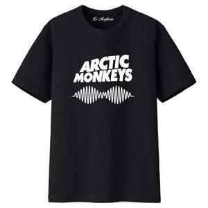 Pode incluir: T-shirt preto com o texto branco "Arctic Monkeys" sobre um desenho de onda sonora branca. A camisa tem gola redonda e mangas curtas. O texto "La Maglieria" está impresso no topo. Uma peça de vestuário com tema musical.