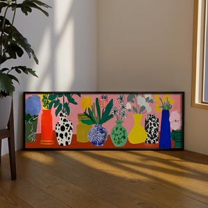 May include: A framed art print depicting a series of vases filled with flowers and foliage. The vases are in diverse colours and patterns, set against a pink backdrop. The artwork includes a vase with a black and white dalmatian pattern. The print is on a wooden floor.