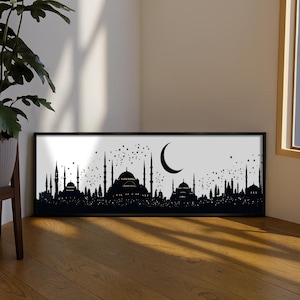 May include: A rectangular wall art piece in a black frame featuring a black silhouette of a mosque skyline with multiple domes and minarets against a white background, accented by a crescent moon and scattered stars in the night sky above.