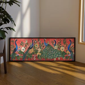 Può includere: Un'opera d'arte incorniciata con un design di pavone. L'opera presenta diversi pavoni con piumaggio blu e verde, su uno sfondo rosso con elementi floreali e di fogliame. La cornice è nera.