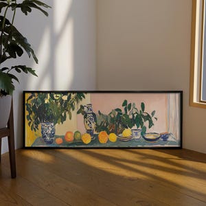 Può includere: Una stampa artistica panoramica incorniciata che raffigura una natura morta con un vaso a motivi blu e bianchi, piante verdi a foglia larga e diversi agrumi gialli e arancioni disposti su una superficie piana su uno sfondo rosa e giallo.
