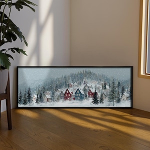 May include: A framed winter landscape painting depicting a snow-covered village amongst evergreen trees. The artwork shows houses with red and blue roofs, set against a backdrop of a snowy forest and a grey sky.