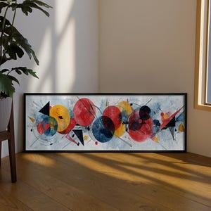 Puede incluir: Una pieza de arte mural rectangular enmarcada que presenta una composición abstracta de círculos superpuestos rojos, amarillos y azules, triángulos negros afilados y líneas finas que se cruzan sobre un fondo de acuarela gris claro con salpicaduras.