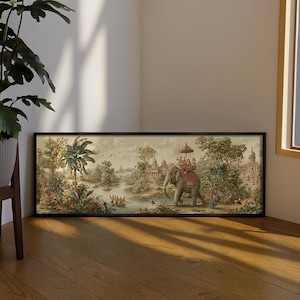 Può includere: Una stampa incorniciata raffigurante un paesaggio indiano con un elefante e delle figure. L'opera presenta un fiume, edifici e vegetazione lussureggiante, con una calda tavolozza di colori. La cornice è nera.