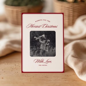 Może przedstawiać: Kartka świąteczna z kremowym tłem i ciemnoczerwoną obwódką. Karta zawiera czarno-białe zdjęcie rodziny. Tekst brzmi „Wishing you the Merriest Christmas” i „With Love, The Smiths”.