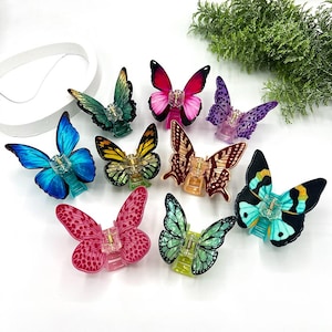 May include: A collection of colorful butterfly hair clips in various shades, including blue, pink, green, and yellow. Each clip features a detailed butterfly design with a clear plastic base, perfect for adding a touch of whimsy to any hairstyle.