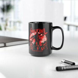 May include: A black ceramic mug featuring a red graphic print of the Silent Hill logo and Pyramid Head character surrounded by figures. The text "SILENT HILL" appears at the top and "RAINING BLOOD" is printed in red at the bottom of the design.