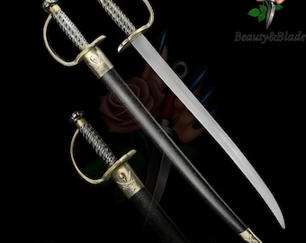 May include: A decorative pirate sword with a curved blade. The hilt features a skull and crossbones design, with a silver and gold finish. The sword is sheathed in a black scabbard. The text "Beauty&Blade" is visible.