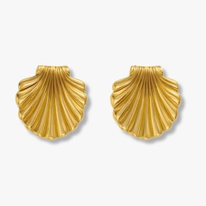 May include: A pair of gold-toned earrings shaped like fan-style seashells. Each earring features a series of vertical, raised ridges radiating from the base to the scalloped top edge, creating a textured, metallic surface with a polished finish.