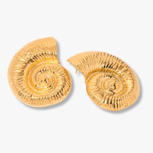 May include: A pair of gold-toned earrings shaped like ammonite fossils. Each earring features a spiraling, ribbed shell design with a polished, reflective surface. The earrings are oriented in opposite directions, showcasing the detailed texture.