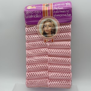 May include: A package of 20 light pink plastic hair rollers with a lattice design. The purple header card features the text sleep easy brush rollers, the fast, easy way to glamorous hair, and an image of a person with styled hair.
