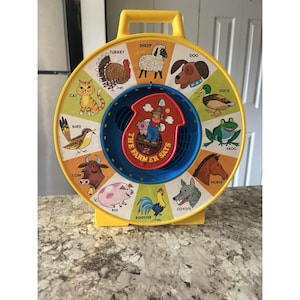 Juego de Mattel See & Say de 1983, modelo "El granjero dice", con cuerda giratoria que funciona.