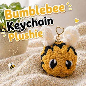 May include: A handmade bumblebee keychain plushie with a yellow and black body, white pom-pom ears, and a gold heart-shaped keyring. The text "Bumblebee Keychain Plushie" is displayed in yellow and black.