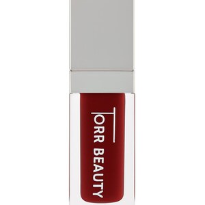 May include: A red liquid lipstick tube with a silver lid. The product is in a clear rectangular container. The text "ORR BEAUTY" is printed vertically in white on the front. The background is white.