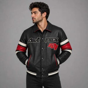 Pu&ograve; includere: Giacca in pelle nera con dettagli rossi e bianchi. La giacca presenta la scritta "Avi Rex" sul petto e un design rosso e bianco sulle maniche. Ha una chiusura con bottoni e un orlo a coste.