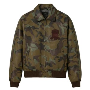 May include: A camouflage-patterned leather jacket in shades of green, brown, and tan. The jacket features a collared neckline, a zipper closure, and a brown ribbed hem and cuffs. A brown patch is sewn on the chest. The brand name is visible on the collar.