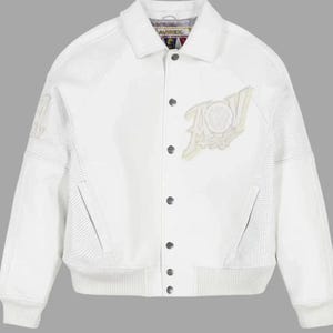 Puede incluir: Chaqueta de cuero blanca con cierre de botones y dobladillo y pu&ntilde;os acanalados. La chaqueta presenta un gran dise&ntilde;o bordado en la parte delantera y detalles perforados en las mangas. El cuello tiene la marca "AVIREX".