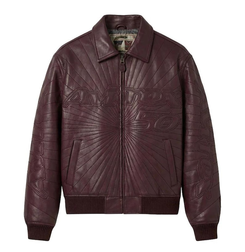 May include: A burgundy leather jacket with a zip-up front, collar, and ribbed cuffs and hem. The jacket features the embossed text "Avirex 50" across the chest and "Avirex" on the sleeves, with a sunburst design radiating from the center.