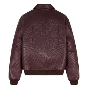 May include: A burgundy leather bomber jacket with a ribbed collar, cuffs, and hem. The back features an embossed design with the text "AVIREX 50 GOLD KICKOFF NY" within a sunburst pattern. The jacket has a classic, sporty style.