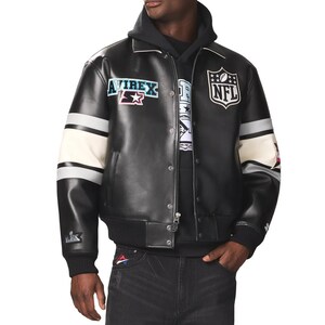 May include: Black leather jacket with white and gray striped sleeves. Features the NFL logo and Avirex patches. The jacket has a zip-up front and a ribbed hem and cuffs. The model is wearing a black hoodie underneath.