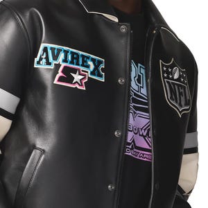 May include: Black leather jacket with white and gray accents. Features the "AVIREX" and "Starter" logos on the chest, and an "NFL" patch on the sleeve. The jacket has a button-up front and a white collar.