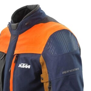 Puede incluir: Chaqueta de moto azul marino y naranja con el logotipo de KTM y la marca Alpinestars. La chaqueta presenta un cuello alto, un panel de malla en el hombro y un bolsillo con cremallera. La chaqueta est&aacute; dise&ntilde;ada para montar en moto.