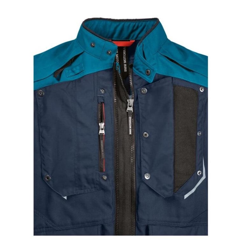 May include: A close-up of a motorcycle jacket in navy blue and teal. The jacket features a high collar, multiple pockets with red zipper pulls, and the BMW Motorrad logo on the zipper. The jacket has a black mesh panel and reflective accents.