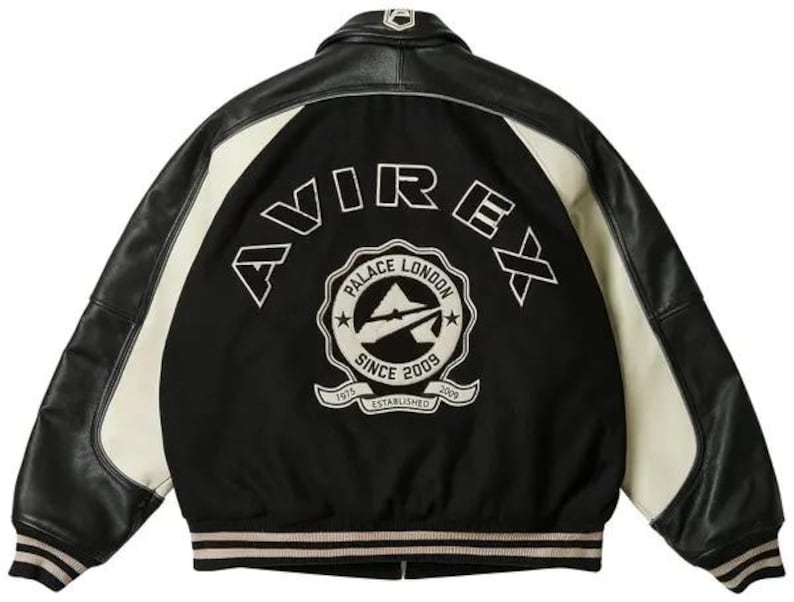 K&ouml;nnte beinhalten: Schwarz-cremefarbene Collegejacke mit Leder&auml;rmeln und schwarzem K&ouml;rper. Auf der R&uuml;ckseite steht das Wort "AVIREX" in Wei&szlig; &uuml;ber einem kreisf&ouml;rmigen Emblem mit der Aufschrift "PALACE LONDON SINCE 2009 ESTABLISHED 1975".