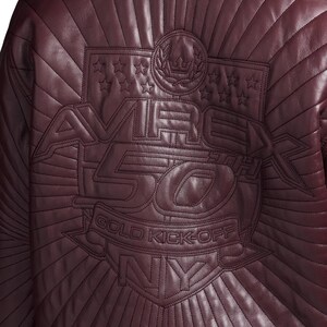 May include: Burgundy leather jacket with quilted stitching. The back features an embossed design with the text "AVIREX 50TH GOLD KICK-OFF NY" and star and crown emblems.