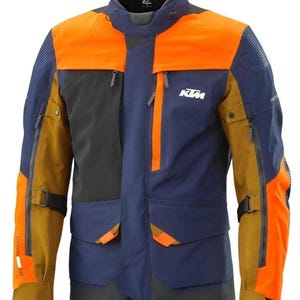 Puede incluir: Chaqueta de moto multicolor con paneles naranjas, azul marino, negros y beige. La chaqueta tiene m&uacute;ltiples bolsillos, cremalleras y el logotipo de KTM en el pecho. Tiene un cuello alto y est&aacute; dise&ntilde;ada para la protecci&oacute;n y la visibilidad.