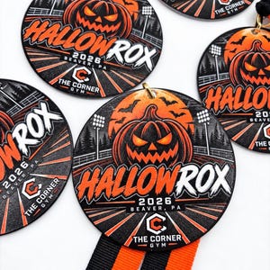 May include: Round black and orange medals featuring a jack-o'-lantern graphic, stadium lights, and the text HALLOWROX 2026 BEAVER, PA and THE CORNER GYM. Each medal includes a black and orange striped ribbon attached to a gold metal loop.