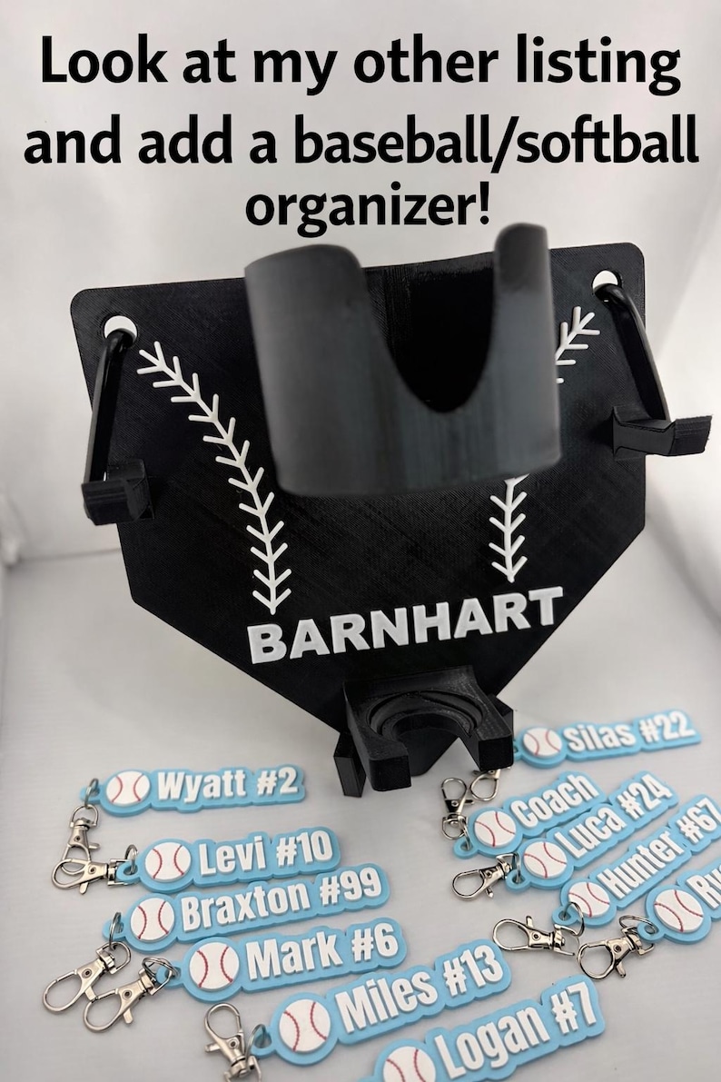Pu&ograve; includere: Un organizer nero per baseball e softball a forma di casa base con portabicchieri centrale, due ganci laterali e il nome BARNHART stampato in bianco. Sotto ci sono diversi portachiavi rettangolari azzurri con grafiche di palline da baseball.