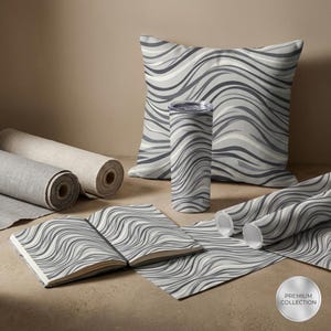 Peut inclure: Une collection d'articles de décoration intérieure avec un motif ondulé gris. Comprend un coussin, un gobelet, un carnet et du tissu roulé. Les articles sont disposés sur une surface neutre, avec un autocollant "Premium Collection".