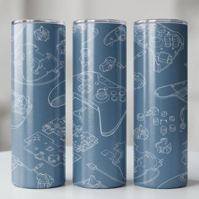 May include: Three blue stainless steel tumblers featuring a white schematic design of video game controllers and components. The design includes controllers, circuit boards, and buttons. The tumblers are cylindrical with a silver rim.