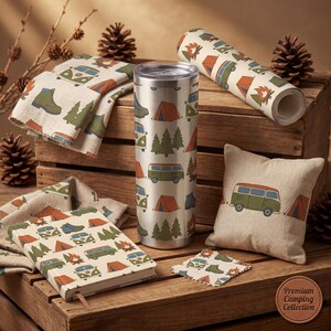 May include: A selection of camping-themed products, including a stainless steel tumbler, a notebook, a cushion, and fabric featuring repeating patterns of tents, trees, and camper vans. The items are displayed on a wooden crate with pine cones and branches.