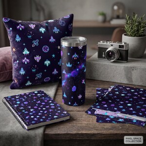 May include: A collection of space-themed items, including a pillow, tumbler, notebook, and stationery. The items feature a dark blue background with pixelated spaceships, planets, and stars in shades of blue, purple, and teal. The Pixel Space Collection logo is in the bottom right corner.