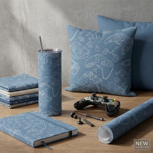 May include: A collection of gaming-themed accessories in shades of blue. The items include a tumbler with a straw, a pillow, a notebook, and a roll of wrapping paper, all featuring a white controller design. A disassembled controller and tools are also present.